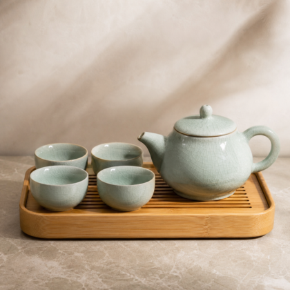 Celadon ceramic teapot with tea cups on tray